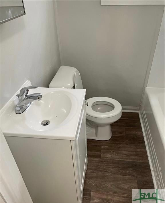 bathroom with vanity, hardwood / wood-style flooring, toilet, and a bathing tub