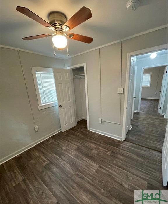 unfurnished bedroom with ornamental molding, dark wood-type flooring, a closet, and ceiling fan