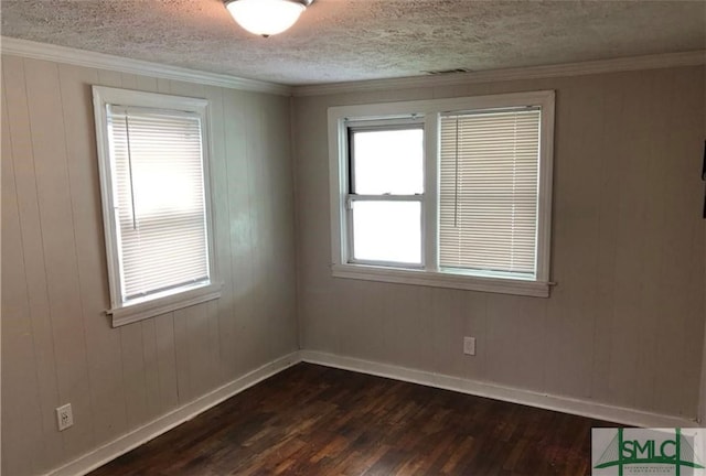 spare room featuring ornamental molding, dark hardwood / wood-style floors, wooden walls, and a textured ceiling