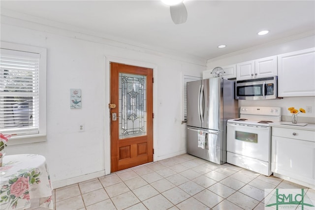 kitchen with appliances with stainless steel finishes, ceiling fan, white cabinets, ornamental molding, and light tile patterned floors