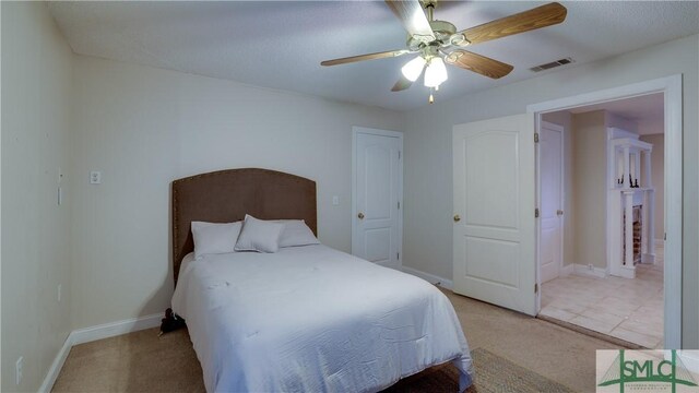 bedroom featuring visible vents, light colored carpet, baseboards, and ceiling fan