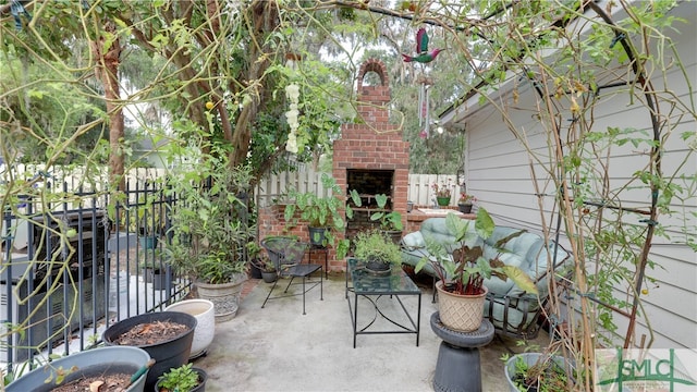 view of patio / terrace featuring fence and an outdoor brick fireplace