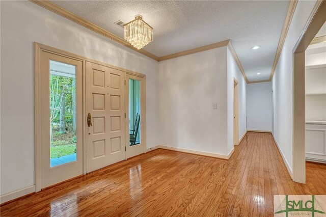 foyer entrance featuring ornamental molding, an inviting chandelier, a textured ceiling, and light wood-type flooring