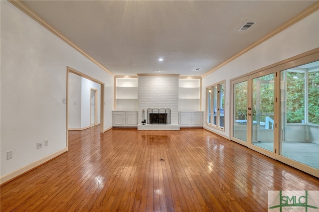 unfurnished living room with crown molding, a brick fireplace, and light hardwood / wood-style floors