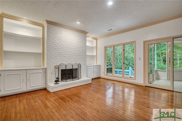 unfurnished living room with ornamental molding, a fireplace, a textured ceiling, and light wood-type flooring