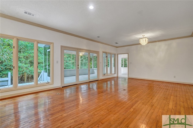 empty room with an inviting chandelier, crown molding, a textured ceiling, and light wood-type flooring