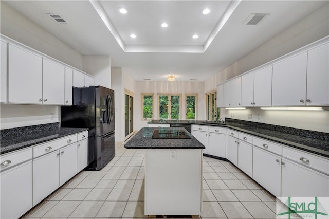 kitchen with a tray ceiling, sink, black appliances, a center island, and white cabinets