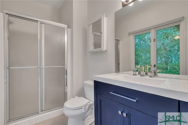 bathroom with vanity, toilet, tile patterned floors, and a shower with door