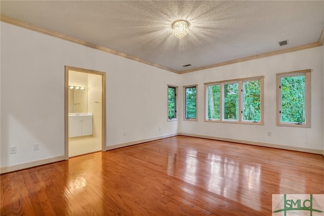 unfurnished room with an inviting chandelier, crown molding, a textured ceiling, and light wood-type flooring