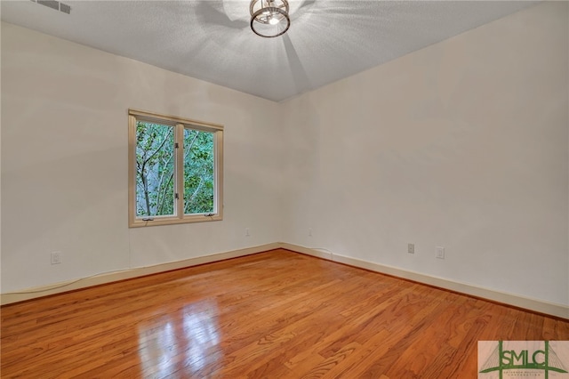 spare room with light hardwood / wood-style floors and a textured ceiling