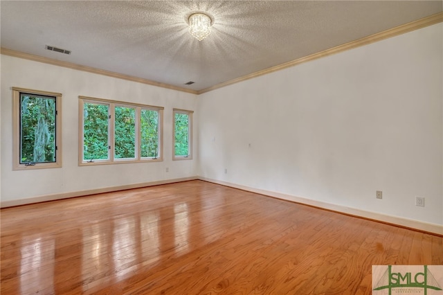 empty room featuring a textured ceiling, light hardwood / wood-style flooring, and ornamental molding