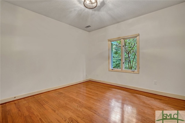 spare room with light hardwood / wood-style flooring and a textured ceiling