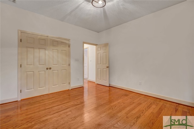 unfurnished bedroom with a closet, light hardwood / wood-style floors, and a textured ceiling