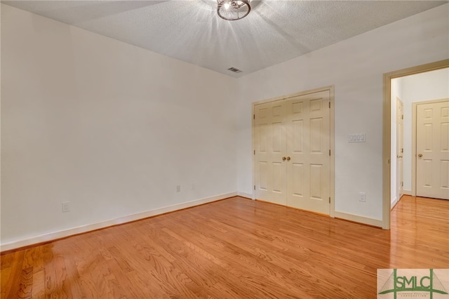 unfurnished bedroom featuring a closet, a textured ceiling, and light hardwood / wood-style floors