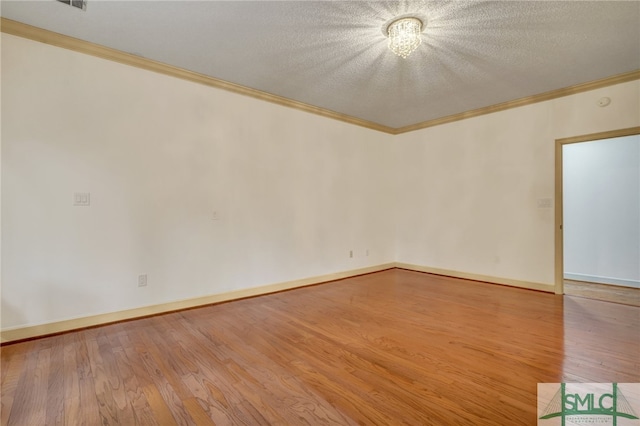 empty room with crown molding, a textured ceiling, and wood-type flooring