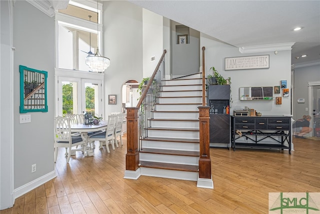 stairway featuring baseboards, wood-type flooring, crown molding, a notable chandelier, and recessed lighting