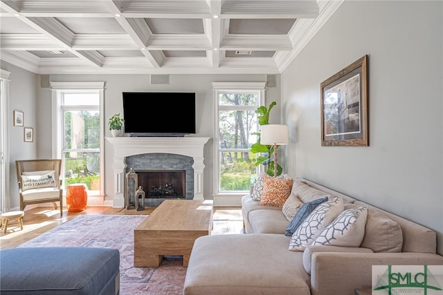 living room featuring coffered ceiling, crown molding, wood-type flooring, beamed ceiling, and a stone fireplace