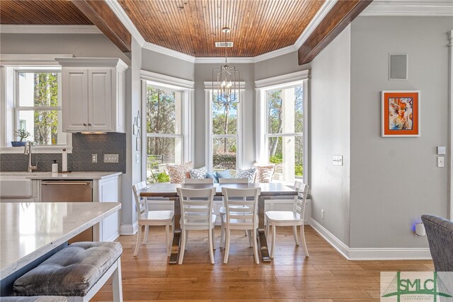 dining area featuring light wood-type flooring, crown molding, and a wealth of natural light