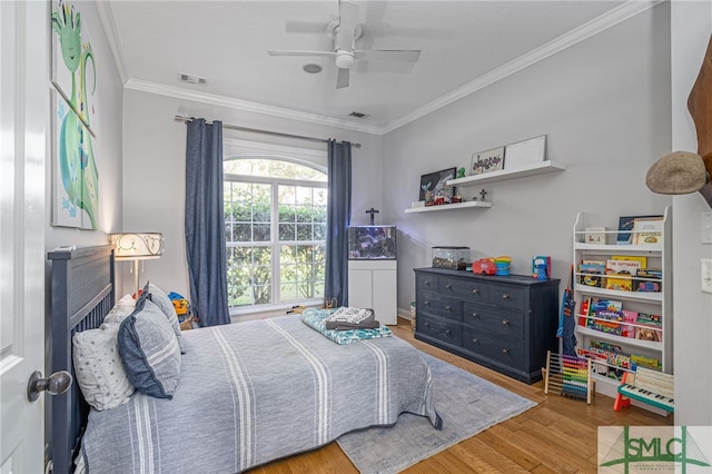 bedroom with a ceiling fan, visible vents, crown molding, and wood finished floors