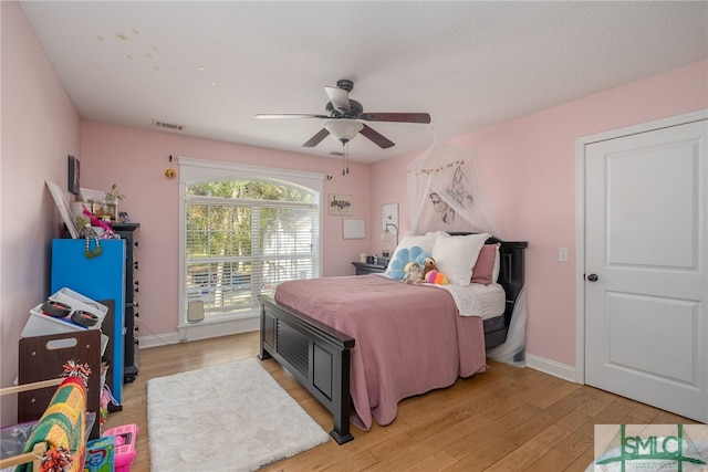 bedroom featuring light wood finished floors, visible vents, baseboards, and a ceiling fan