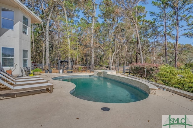 view of pool featuring a patio, fence, and a pool with connected hot tub