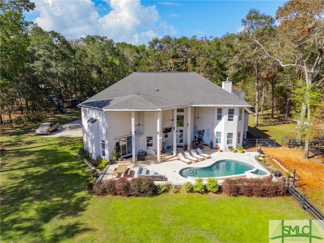 back of property with a yard, a chimney, a patio, fence, and an outdoor pool