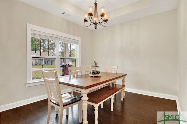 dining space featuring an inviting chandelier, dark hardwood / wood-style floors, and a raised ceiling