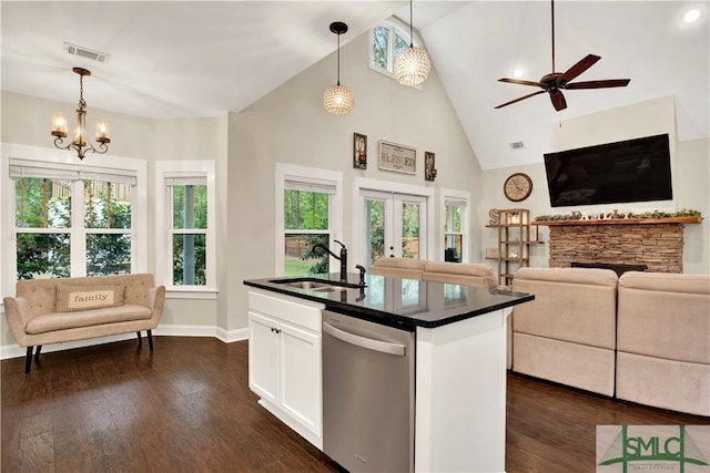 kitchen with a kitchen island with sink, hanging light fixtures, sink, stainless steel dishwasher, and white cabinets