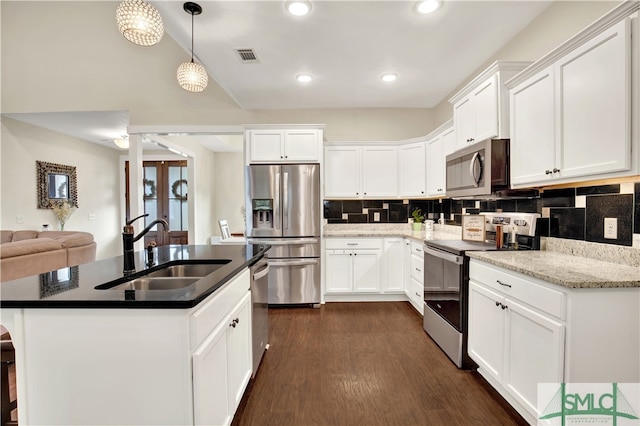 kitchen with appliances with stainless steel finishes, sink, pendant lighting, white cabinets, and dark hardwood / wood-style floors