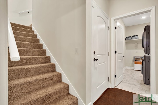 stairs with wood-type flooring and stacked washer and clothes dryer