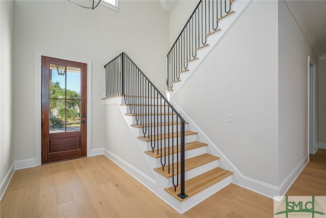 entryway with a towering ceiling and light hardwood / wood-style flooring