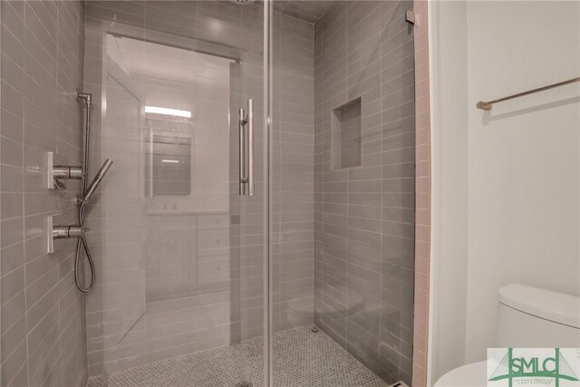 bathroom featuring toilet and a shower with shower door