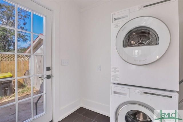 laundry room with dark tile patterned flooring, stacked washer / drying machine, and ornamental molding