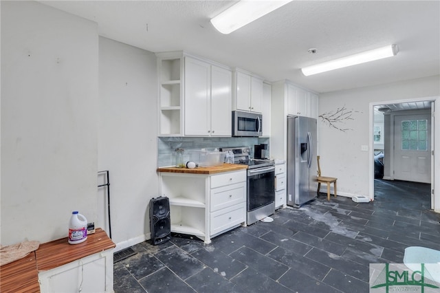 kitchen with white cabinets, a textured ceiling, stainless steel appliances, wooden counters, and decorative backsplash