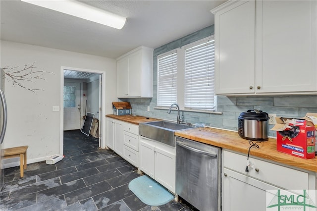 kitchen with decorative backsplash, white cabinets, stainless steel dishwasher, butcher block counters, and sink