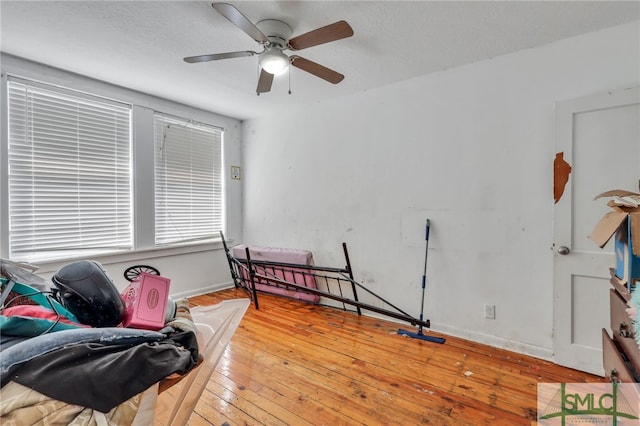 living area with ceiling fan, a textured ceiling, and light wood-type flooring