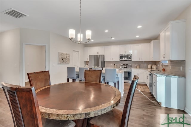 dining area with hardwood / wood-style flooring, a notable chandelier, and sink