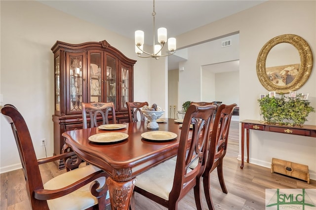 dining area with hardwood / wood-style flooring and a notable chandelier