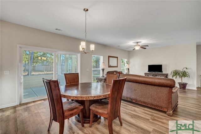 dining space with wood-type flooring and ceiling fan with notable chandelier