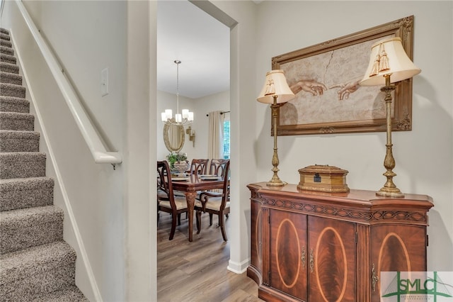 staircase featuring hardwood / wood-style floors and an inviting chandelier