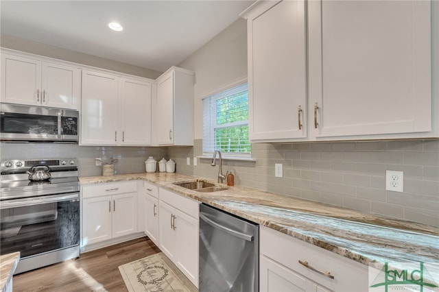 kitchen with white cabinets, light stone counters, sink, and appliances with stainless steel finishes