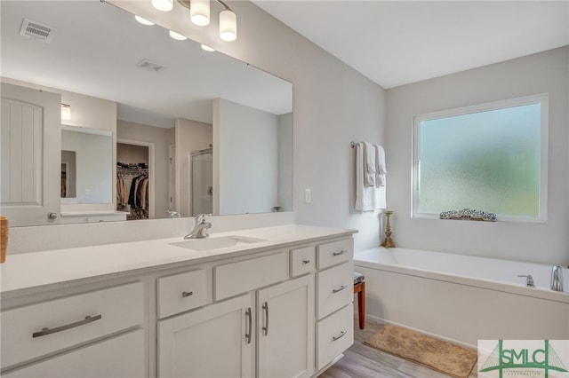 bathroom with separate shower and tub, vanity, and hardwood / wood-style flooring