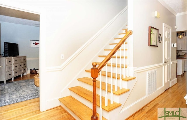 stairs featuring hardwood / wood-style floors and crown molding