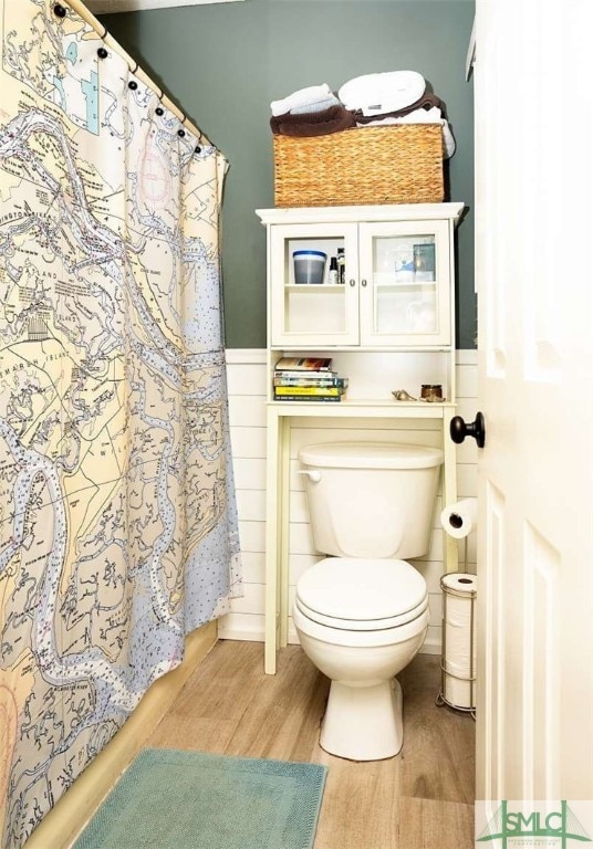 bathroom with toilet, wood-type flooring, and tile walls