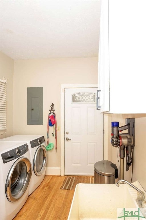 laundry area with electric panel, light hardwood / wood-style flooring, and washer and clothes dryer