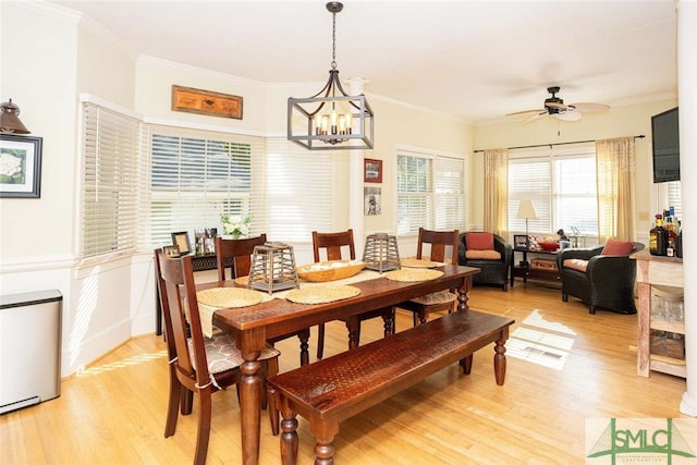 dining area with ceiling fan with notable chandelier, light wood-type flooring, and crown molding