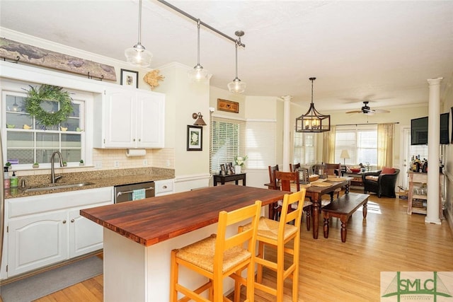 kitchen with white cabinets, light hardwood / wood-style floors, sink, and hanging light fixtures