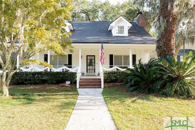 view of front of house with a porch, a shingled roof, a front yard, and a chimney