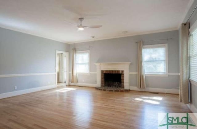 unfurnished living room with crown molding, a ceiling fan, wood finished floors, and a fireplace