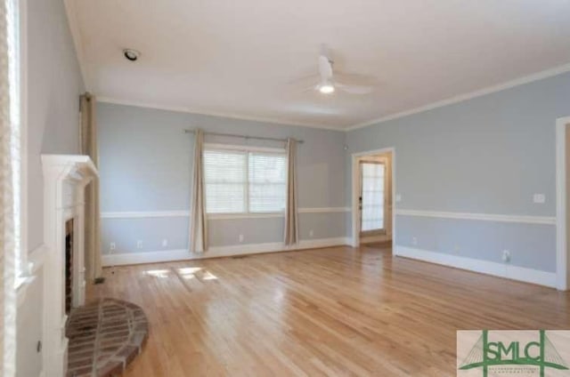 unfurnished living room with crown molding, a brick fireplace, ceiling fan, and wood finished floors